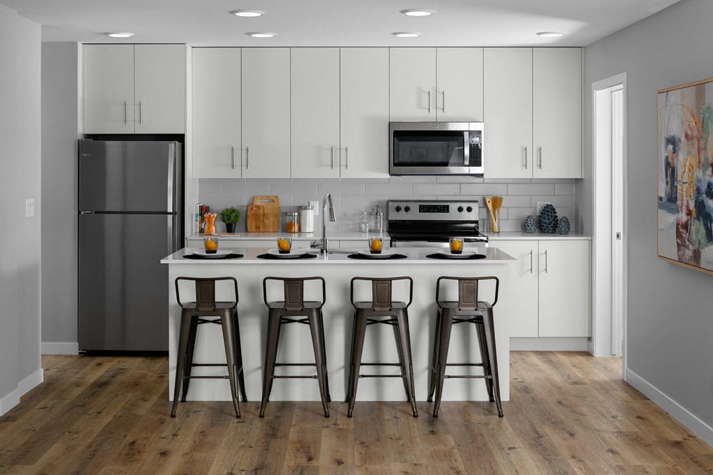 A kitchen with white cabinets and a wooden floor.