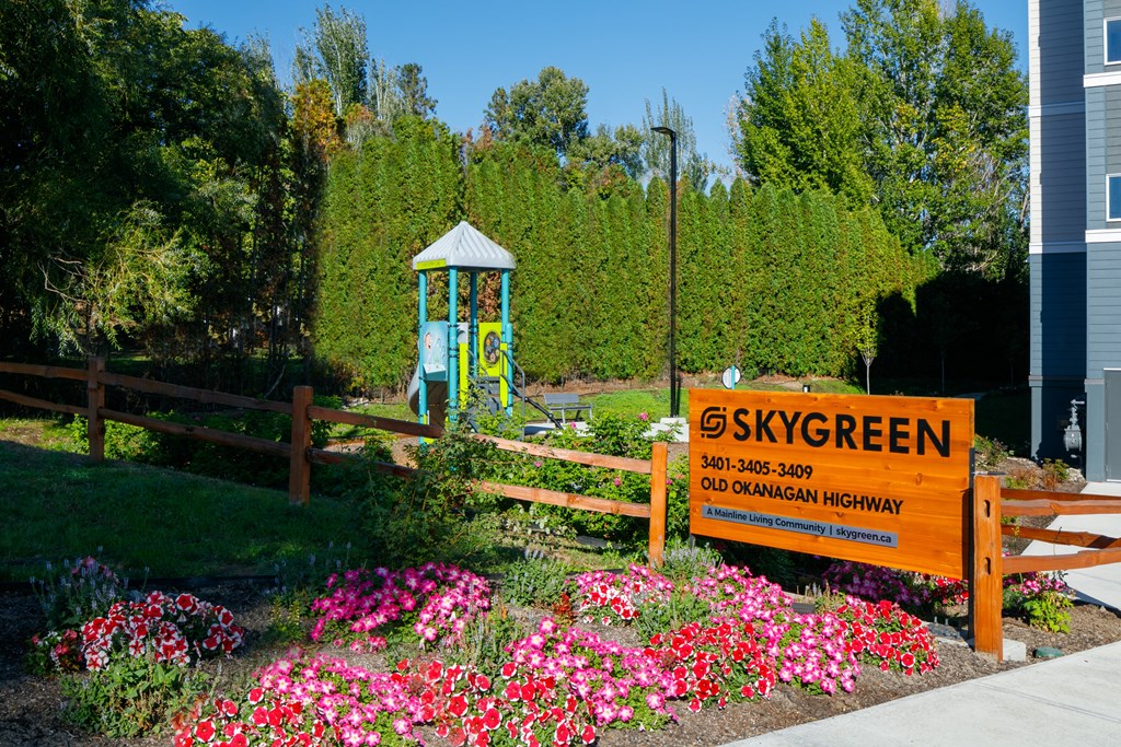 a garden with pink and purple flowers and a blue playground in the background