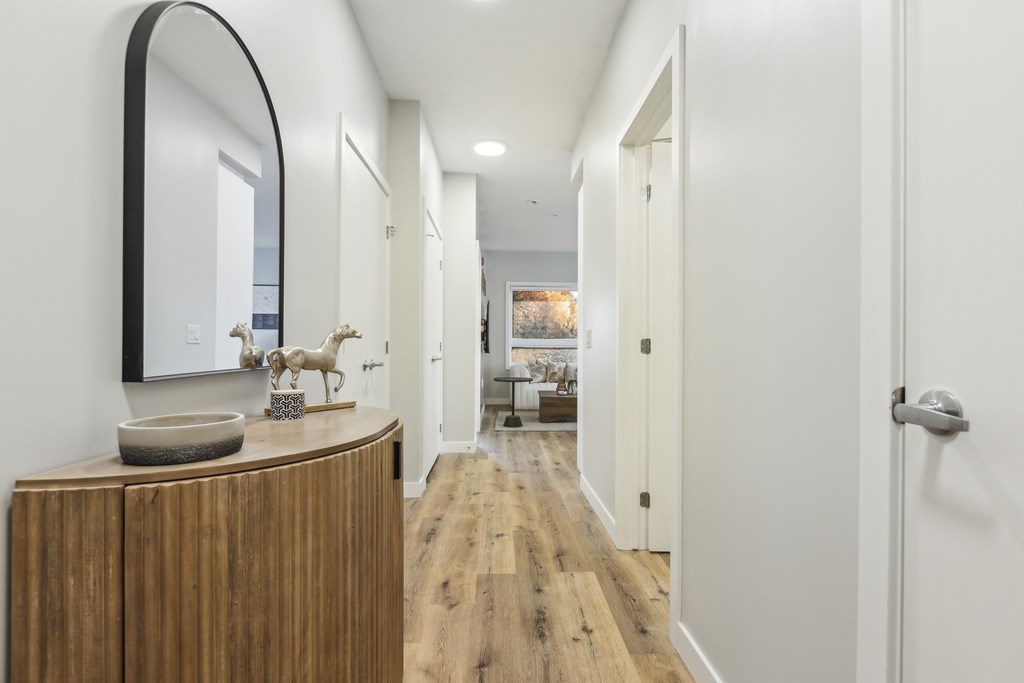 A hallway with a wooden floor and white walls.