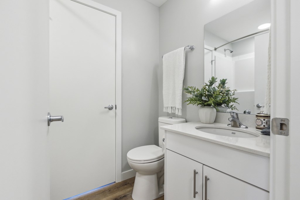 A white bathroom with a toilet, sink, and mirror.
