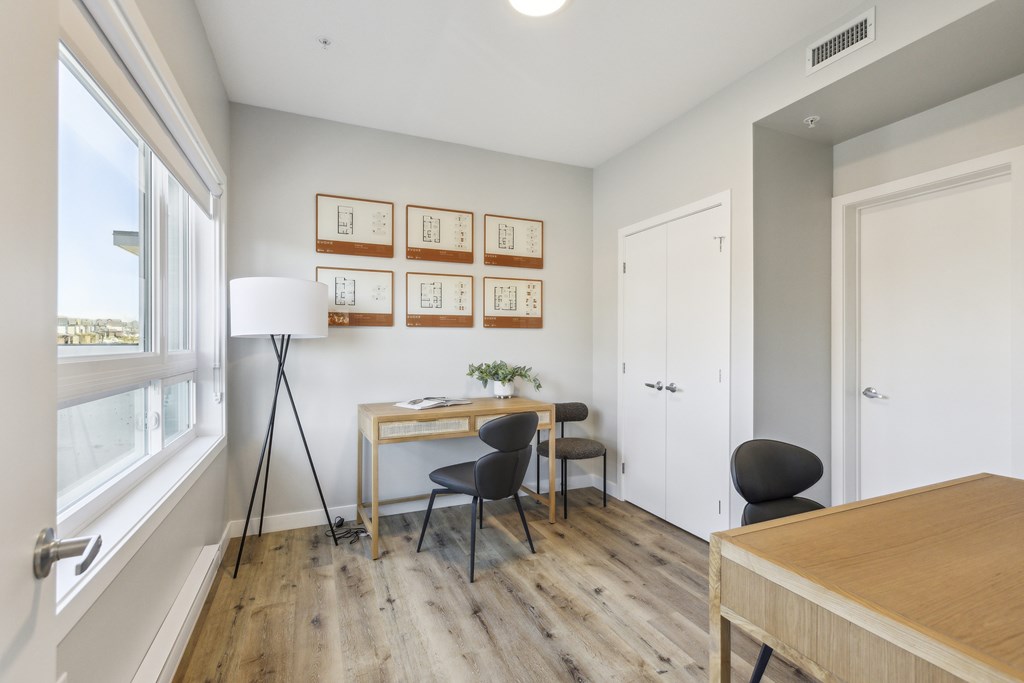 A room with a desk, chairs, and pictures on the wall.