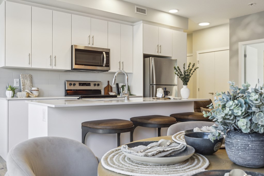 A modern kitchen with white cabinets and a breakfast table set.