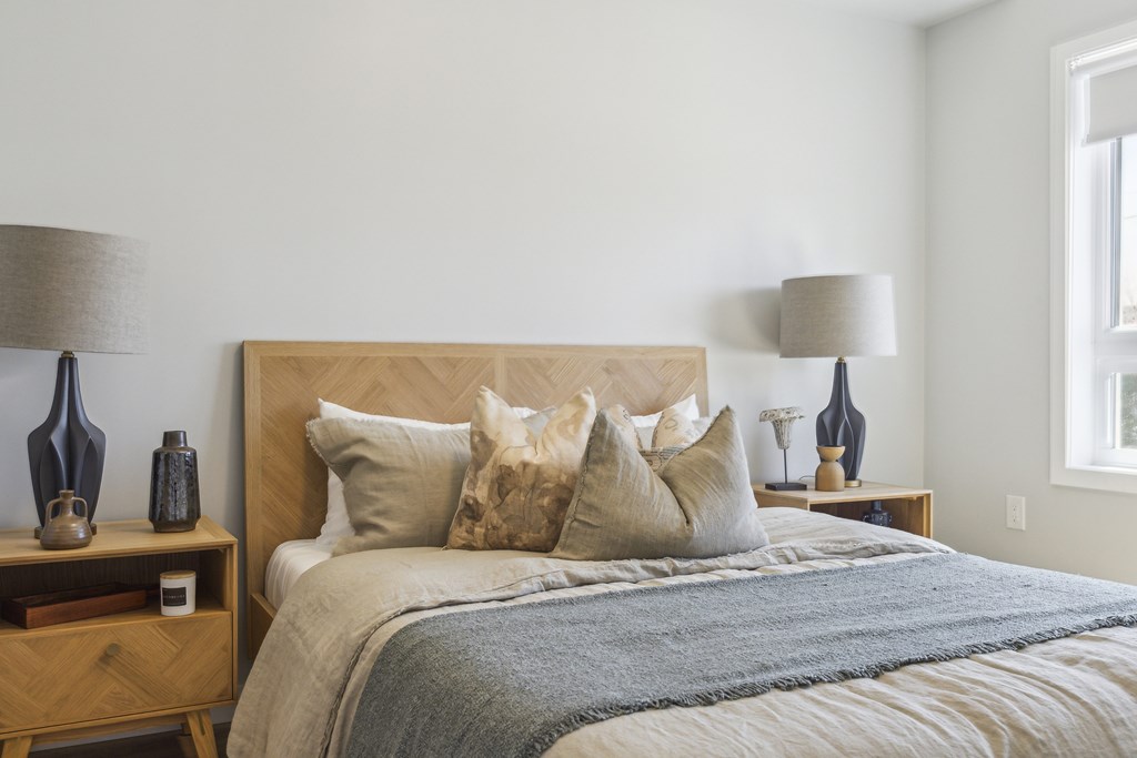 A bed with a wooden headboard and a grey blanket is in the image.