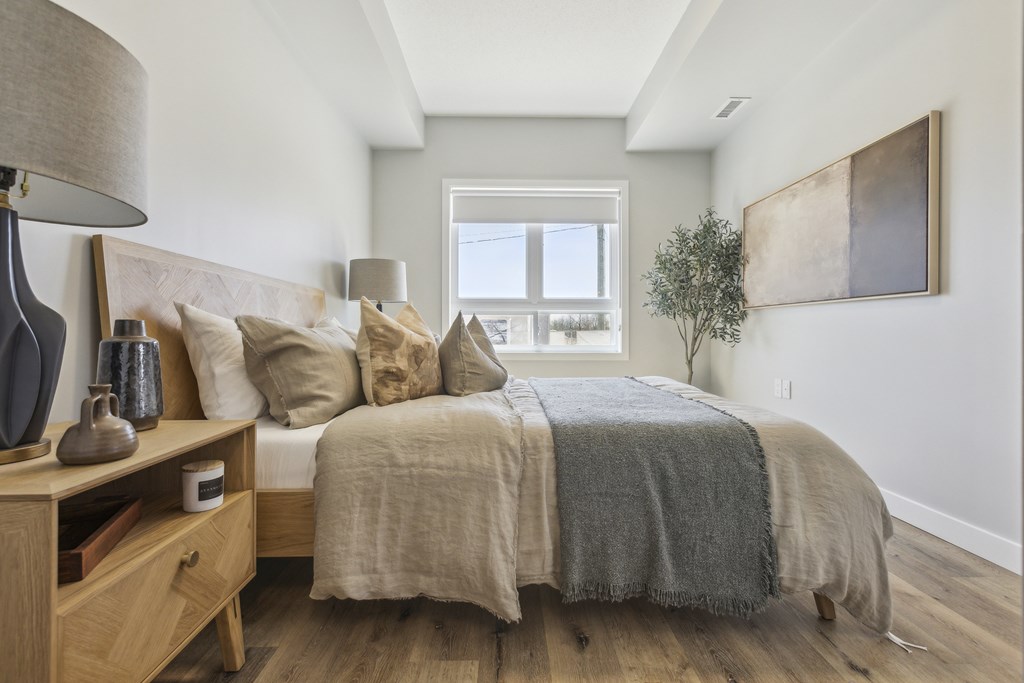 A bedroom with a bed, nightstand, and lamp.