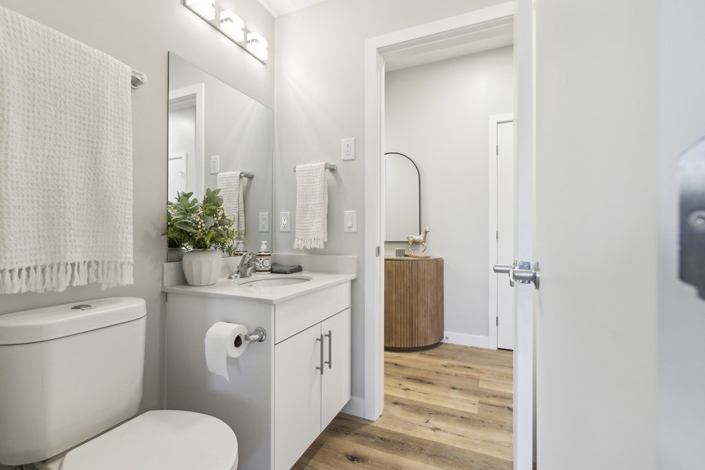 A white bathroom with a toilet, sink, and mirror.