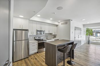 a kitchen with white cabinets and stainless steel appliances and a wood floor