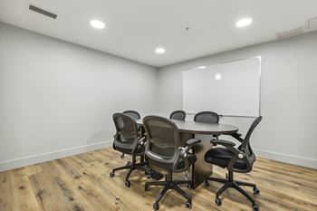 a conference room with a table and chairs and a whiteboard on the wall