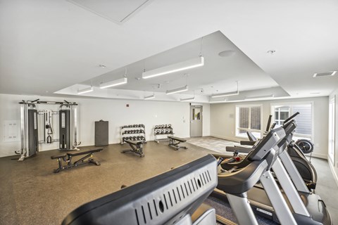a gym with treadmills and other exercise equipment in a room with windows