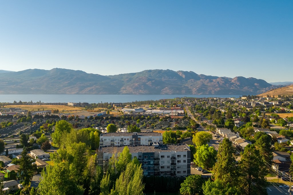 a cityscape with a lake and mountains in the background