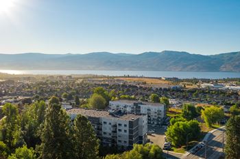 an aerial view of a city with a lake and mountains in the background