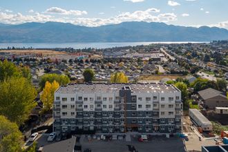 an aerial view of a large apartment building with a lake and mountains in the background
