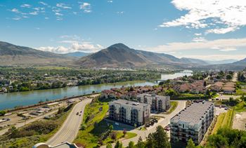 A scenic view of a river, mountains, and a town with buildings.