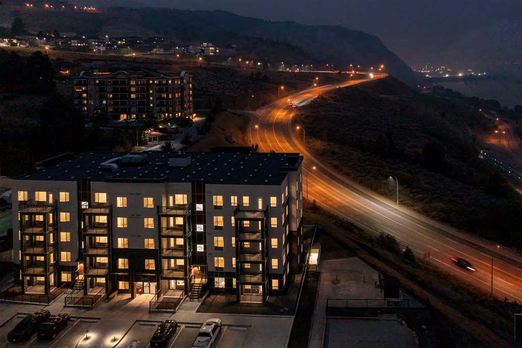 a cityscape at night with a building in the foreground and a road in the background