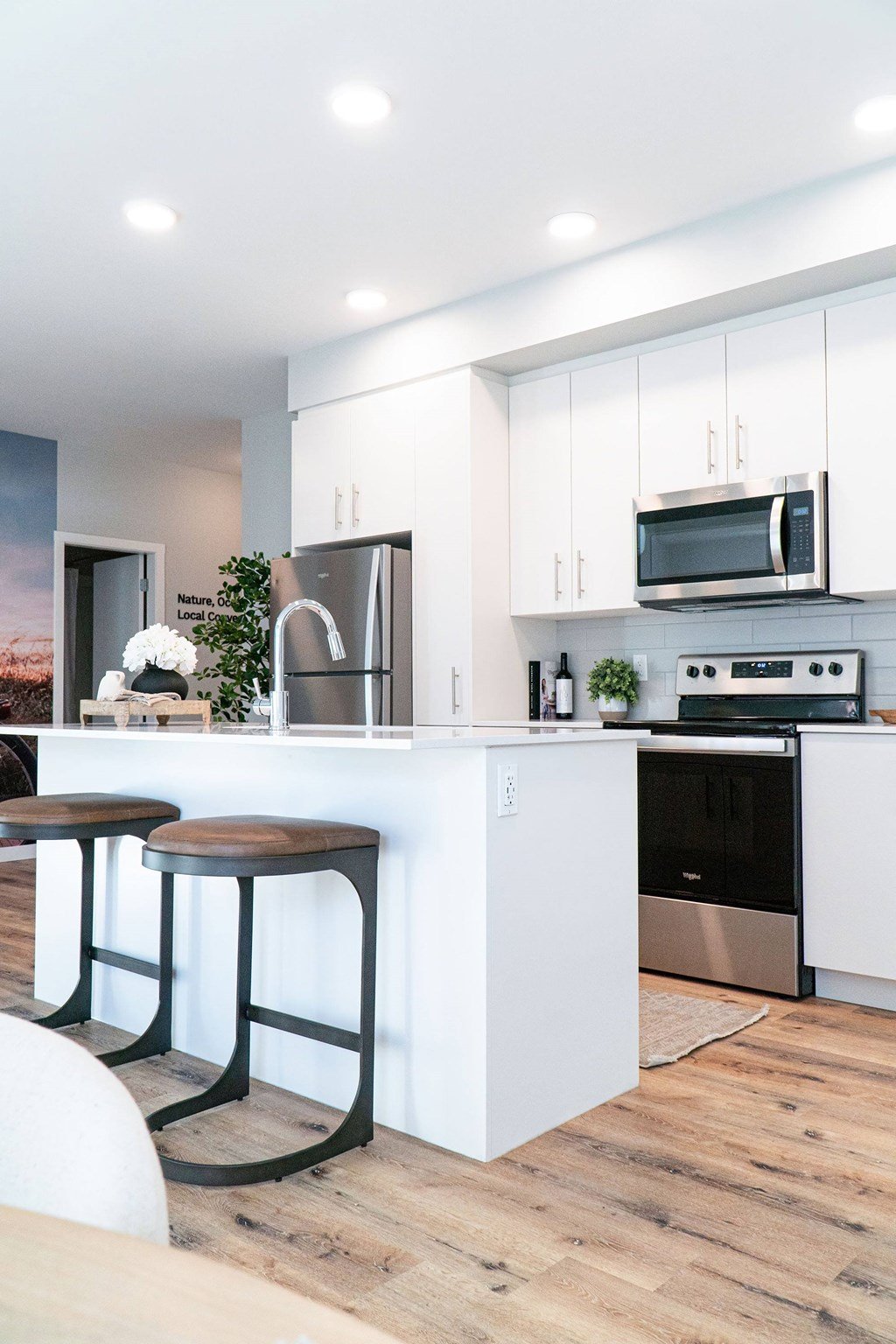 A modern kitchen with white cabinets and a wooden floor.