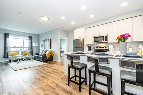 a living room with a kitchen and a table with three stools