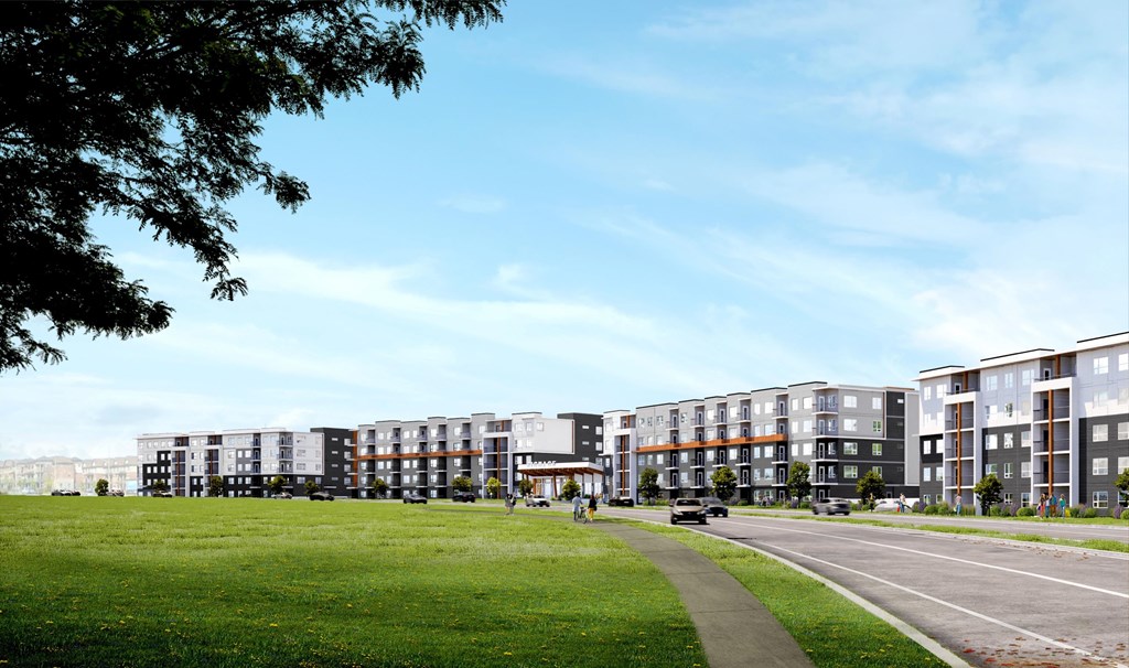 A row of modern apartment buildings with a green lawn in front.
