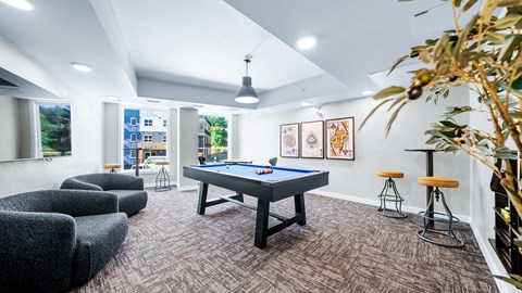 A room with a pool table and bar stools.