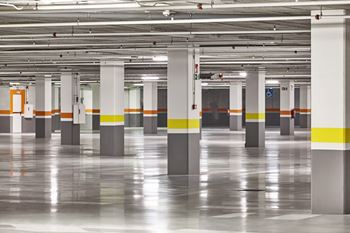 A parking garage with grey pillars and yellow stripes.