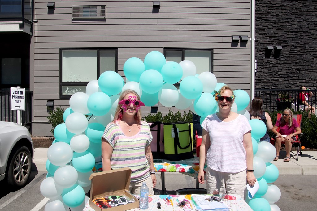 two women standing in front of a table covered with balloons