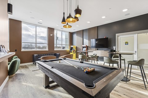 A pool table in a room with a television and chairs.