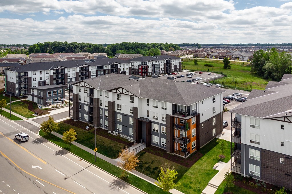 an aerial view of a large apartment complex with a green field in the background