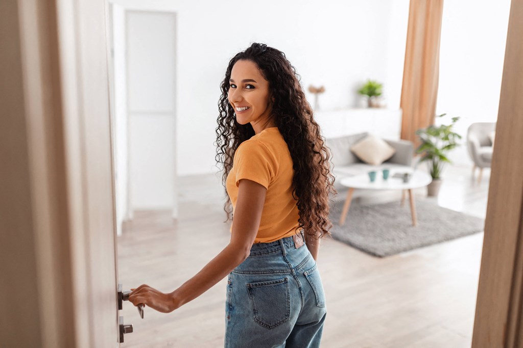 young woman opening the door to her apartment