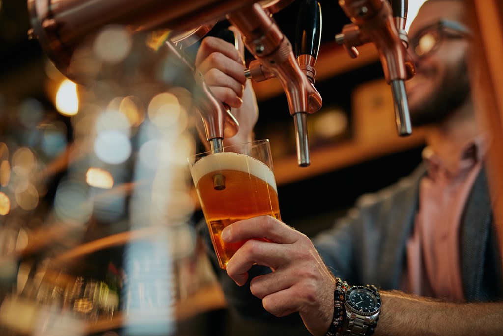 A man is pouring a beer from a tap into a glass.
