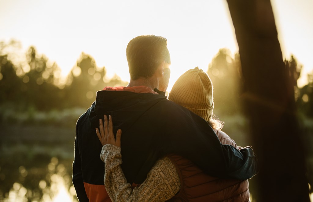 A couple is hugging each other in a sunny outdoor setting.