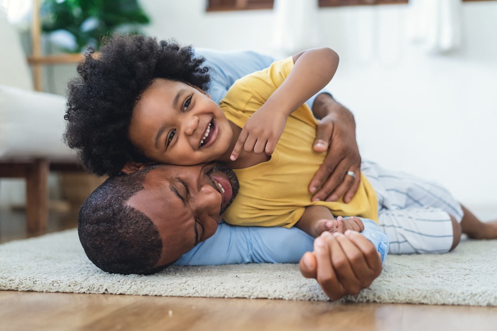 a father and son laying on the floor of a living room
