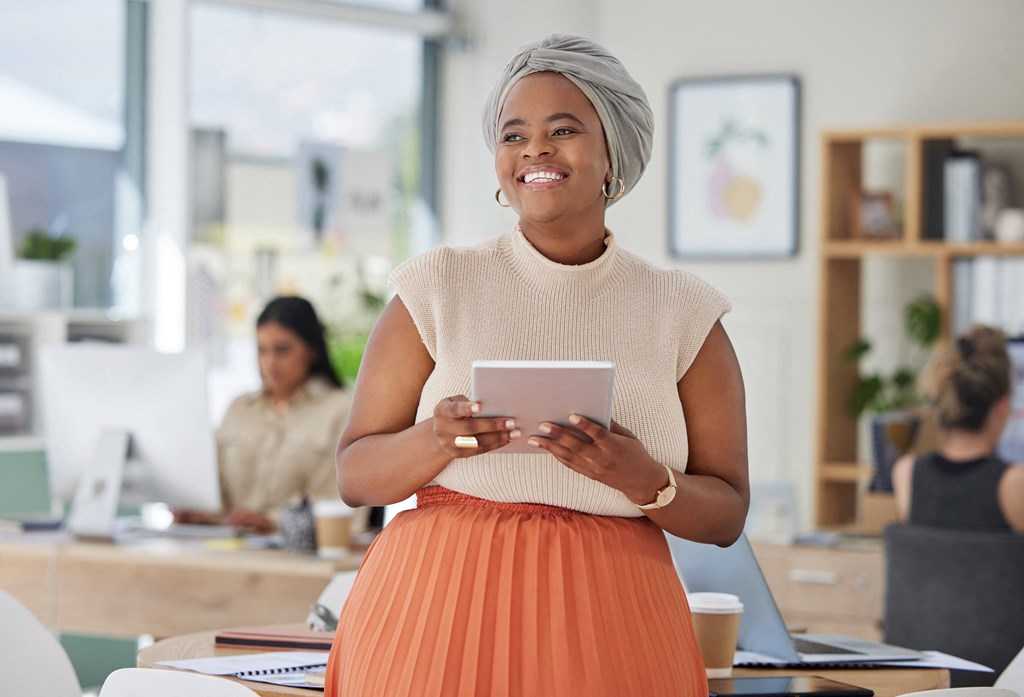 a woman standing in an office holding a tablet