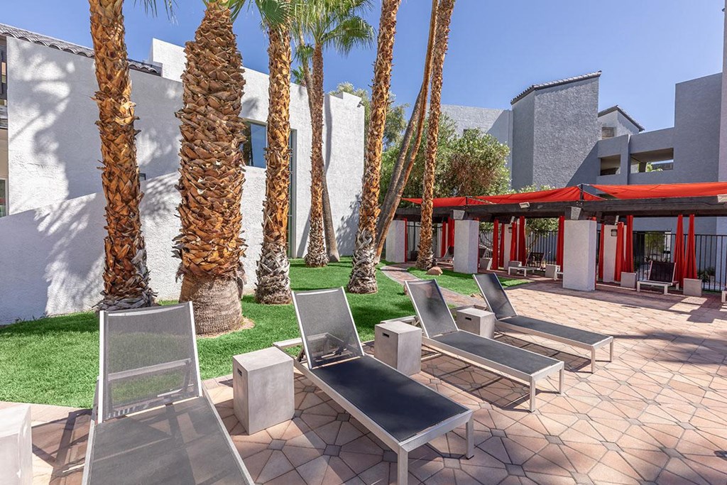 a patio with chairs and palm trees at Evoq Apartment Homes, Nevada  