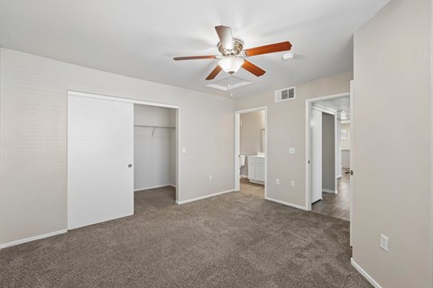 A spacious room with a ceiling fan and carpeted floor.