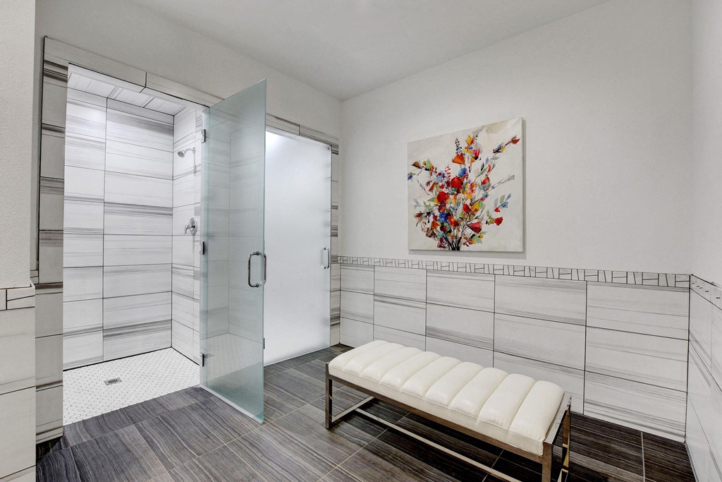 a white bathroom with a shower and a bench at Evoq Apartment Homes, Las Vegas, NV  