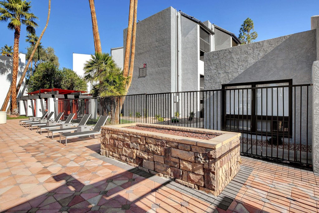 a fenced in area with a stone fountain and chairs at Evoq Apartment Homes, Las Vegas, 89169  