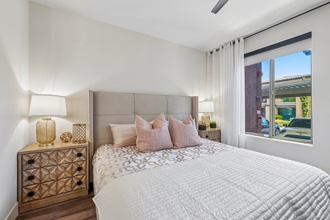 A bedroom with a large bed and a wooden nightstand with a lamp on it.