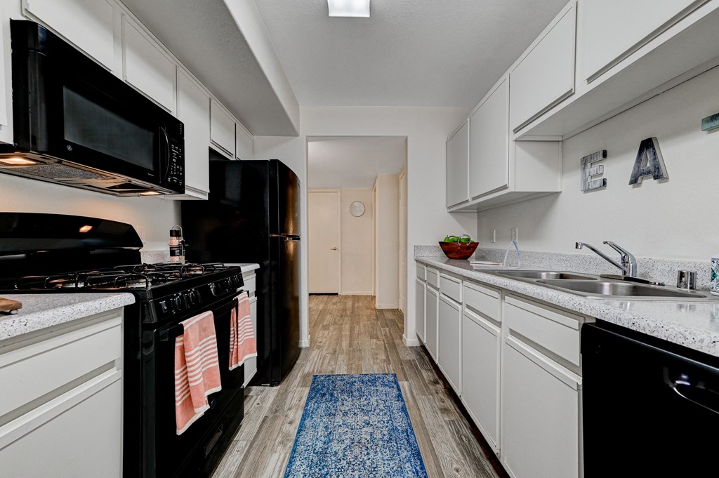 a kitchen with white cabinets and black appliances