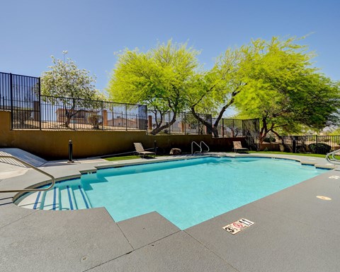 a swimming pool with a fence around it and trees in the background at Maryland Villas Apartments, Las Vegas