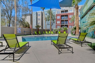 a swimming pool with green lounge chairs and blue umbrellas