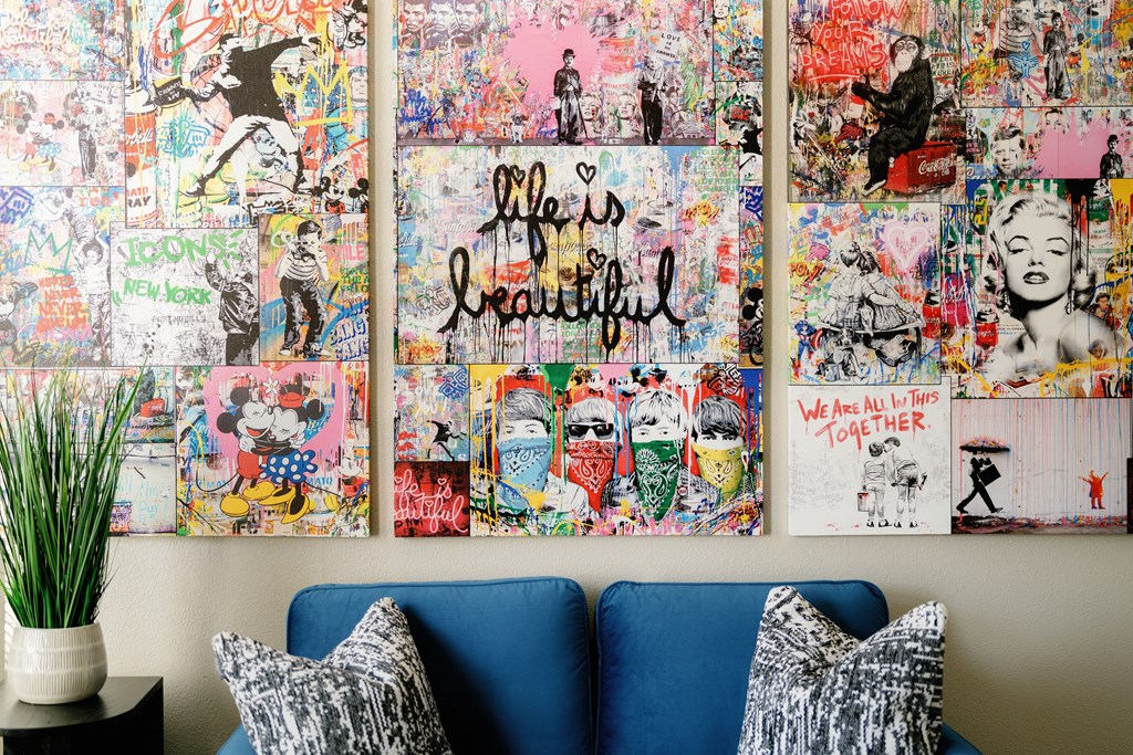 a wall full of artwork and a couch with pillows