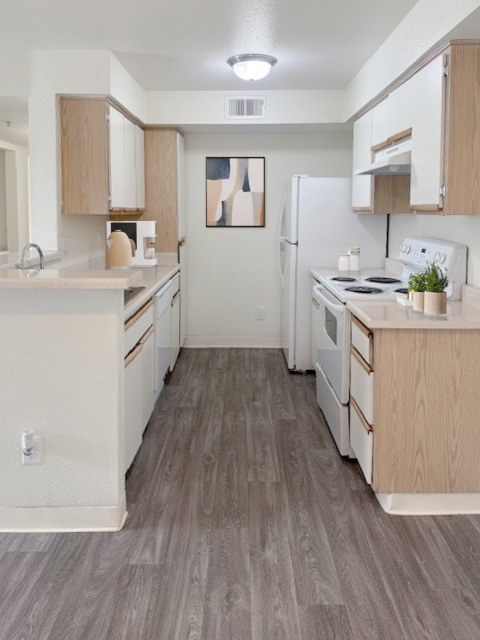 A kitchen with white appliances and wooden cabinets.