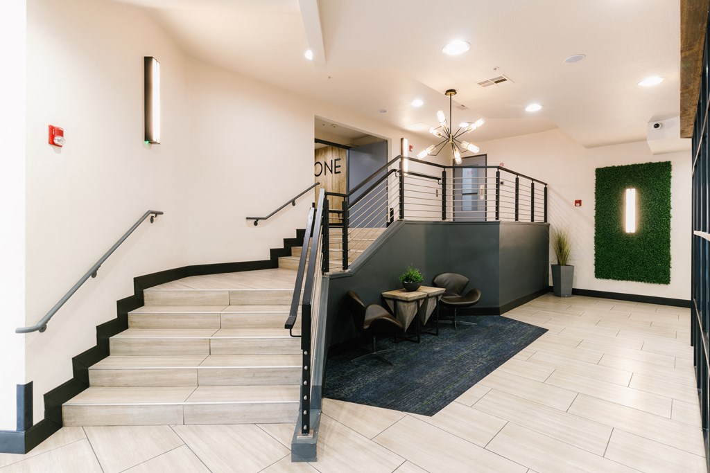 a lobby with stairs and a table with chairs