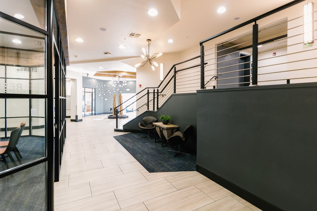 the lobby of a building with a staircase and a table and chairs