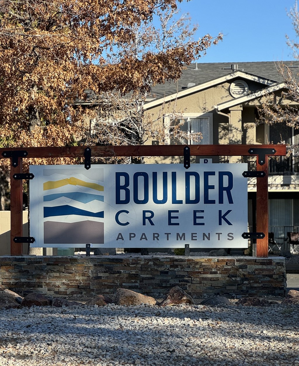 A sign for Boulder Creek Apartments is displayed in front of a building.