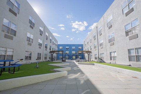 an exterior view of an apartment building with grass and benches  at The Onyx at 695, Reno