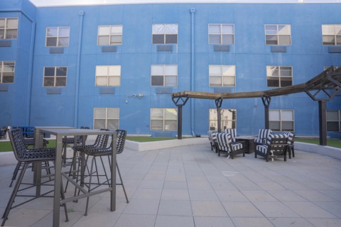 a patio with tables and chairs in front of a blue building at The Onyx at 695, Nevada