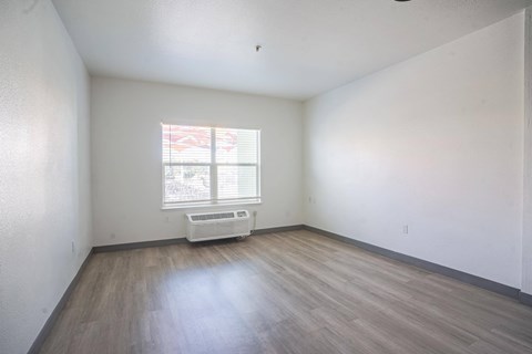 the living room of an empty house with wooden floors and a window at The Onyx at 695, Reno, NV