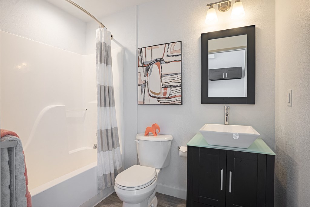 a bathroom with a toilet sink and mirror and a shower at ParcOne60, Reno, 89501