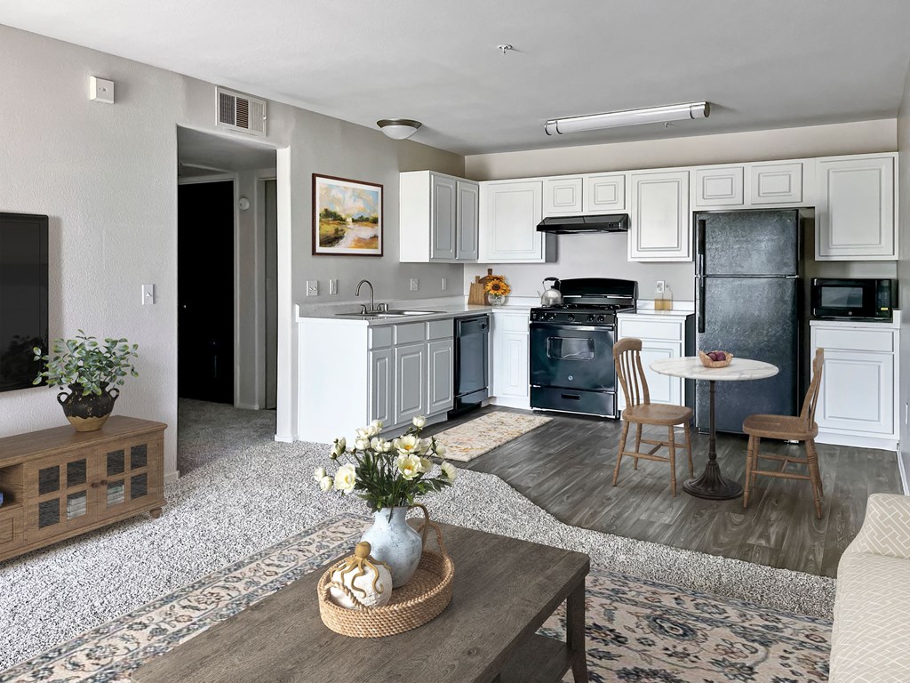 a kitchen and living room with white cabinets and black appliances