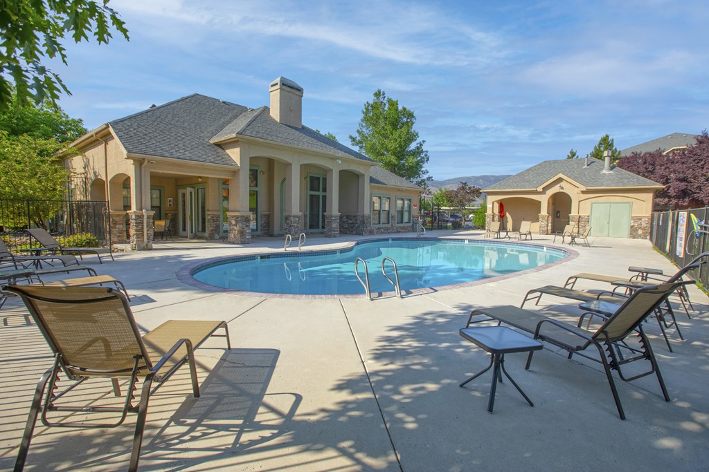 a pool with chairs and a house next to it