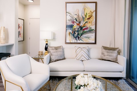 A white sofa with a gold frame and a white chair with a gold frame in a living room.